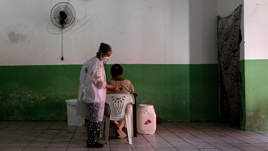 Une médecin soigne une patient, qui tourne le dos à l’objectif