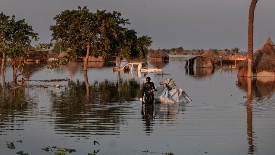 Un homme marche dans un village inondé. 
