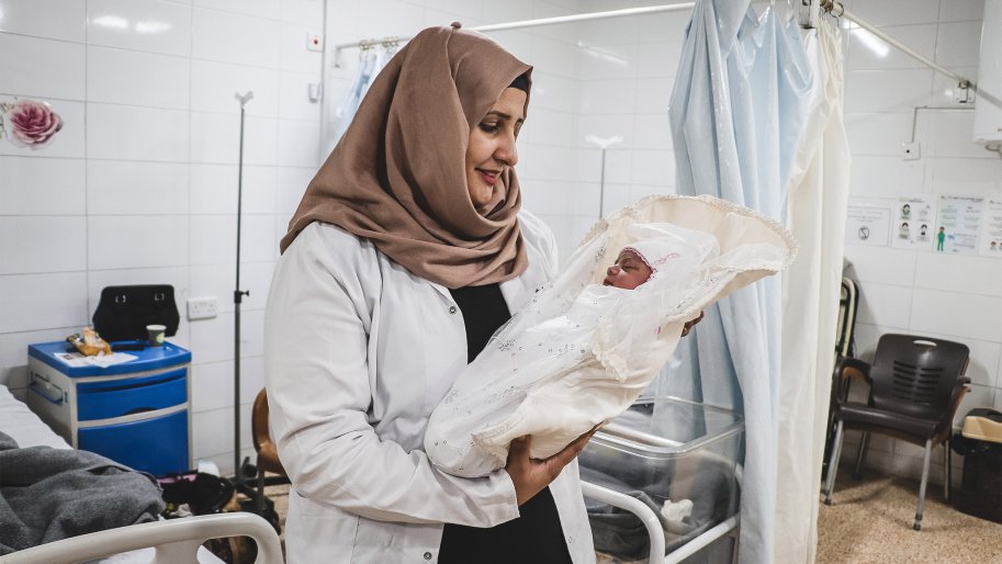Rahma Adla Abdallah, une sage-femme superviseuse tient un nouveau né dans ses bras.