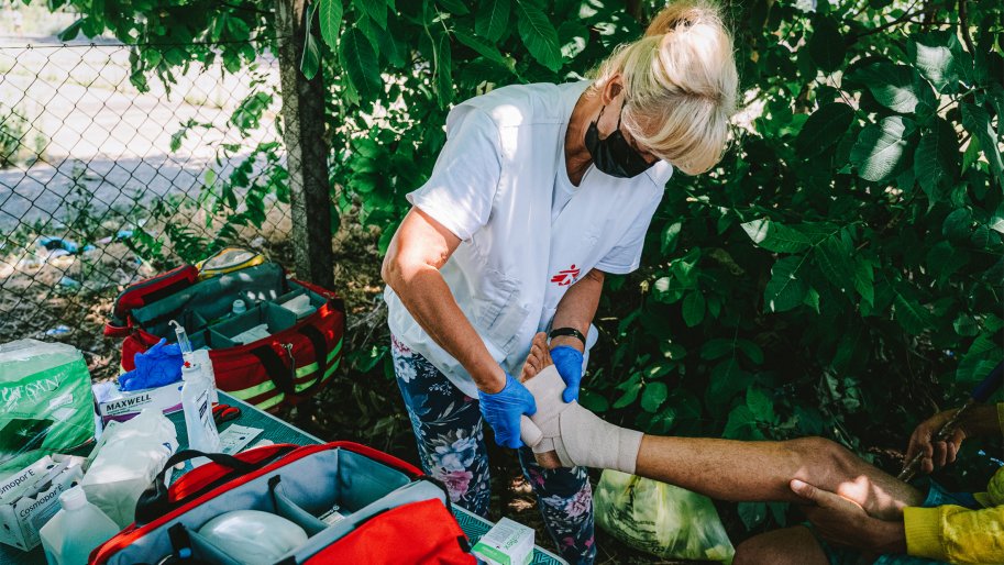 Une infirmière MSF bande la cheville d'un patient lors d'une consultation médicale de la clinique mobile MSF.