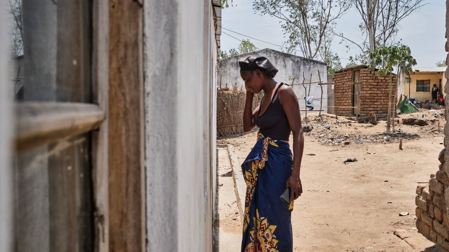 Une femme devant une maison au Malawi.