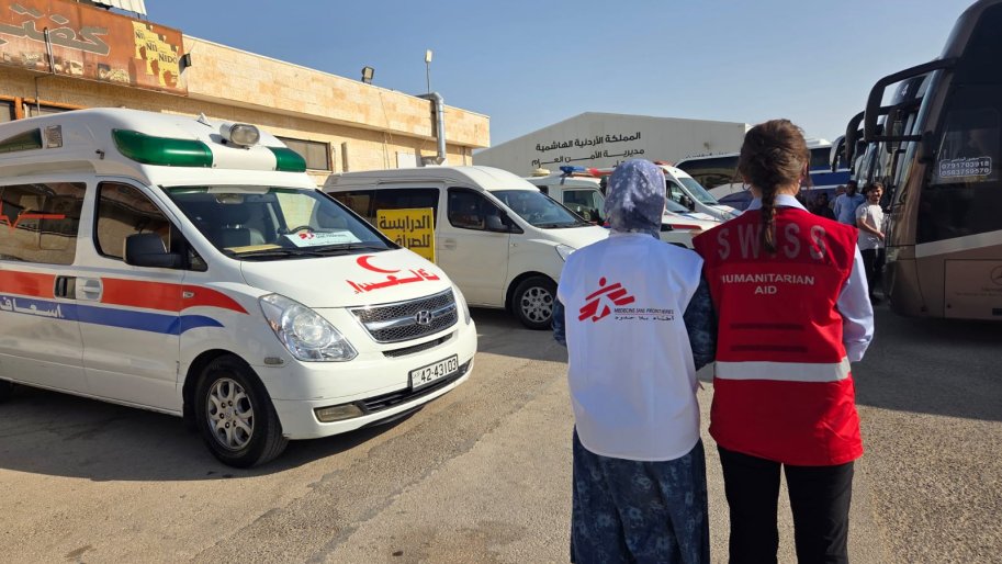 Deux personnes se tenant debout devant une ambulance Médecins Sans Frontières et Croissant-Rouge Jordanien.