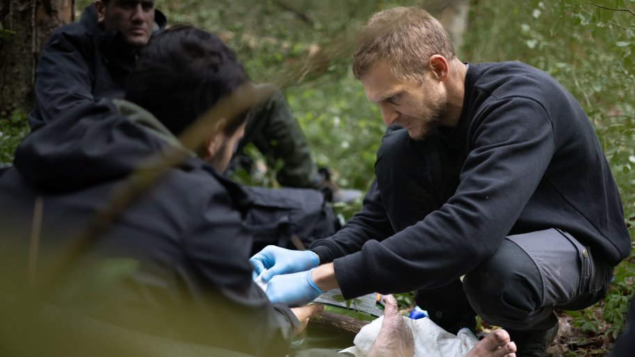 Un secouriste soigne les blessures d'une personne migrante, dans la forêt de Bialovèse en 2024. 