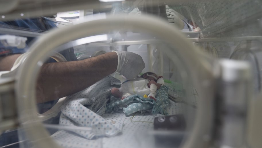 Un membre du personnel de l'hôpital Al-Helou, situé à Gaza, dans les territoires palestiniens occupés, s'occupe d'un nouveau-né de faible poids placé dans une couveuse. 