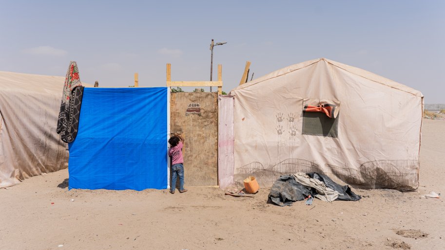 Une petite fille frappe à la porte de sa tente, à l'entrée du camp d'Atira, dans le gouvernorat de Lahj. 