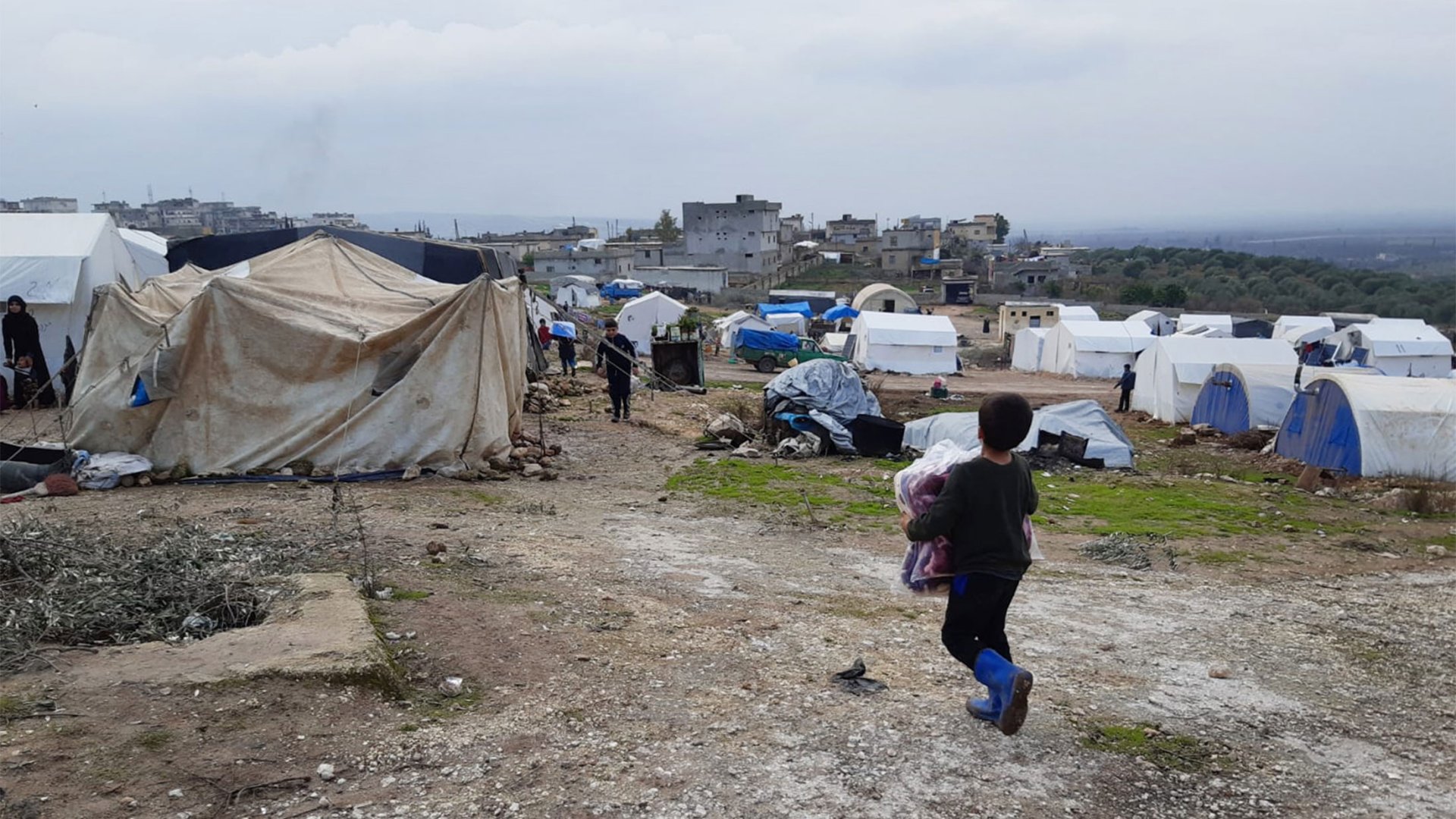 Ein Kind kehrt mit den von MSF verteilten Decken zum Zelt zurück. Camp in Nordwestsyrien, Januar 2020