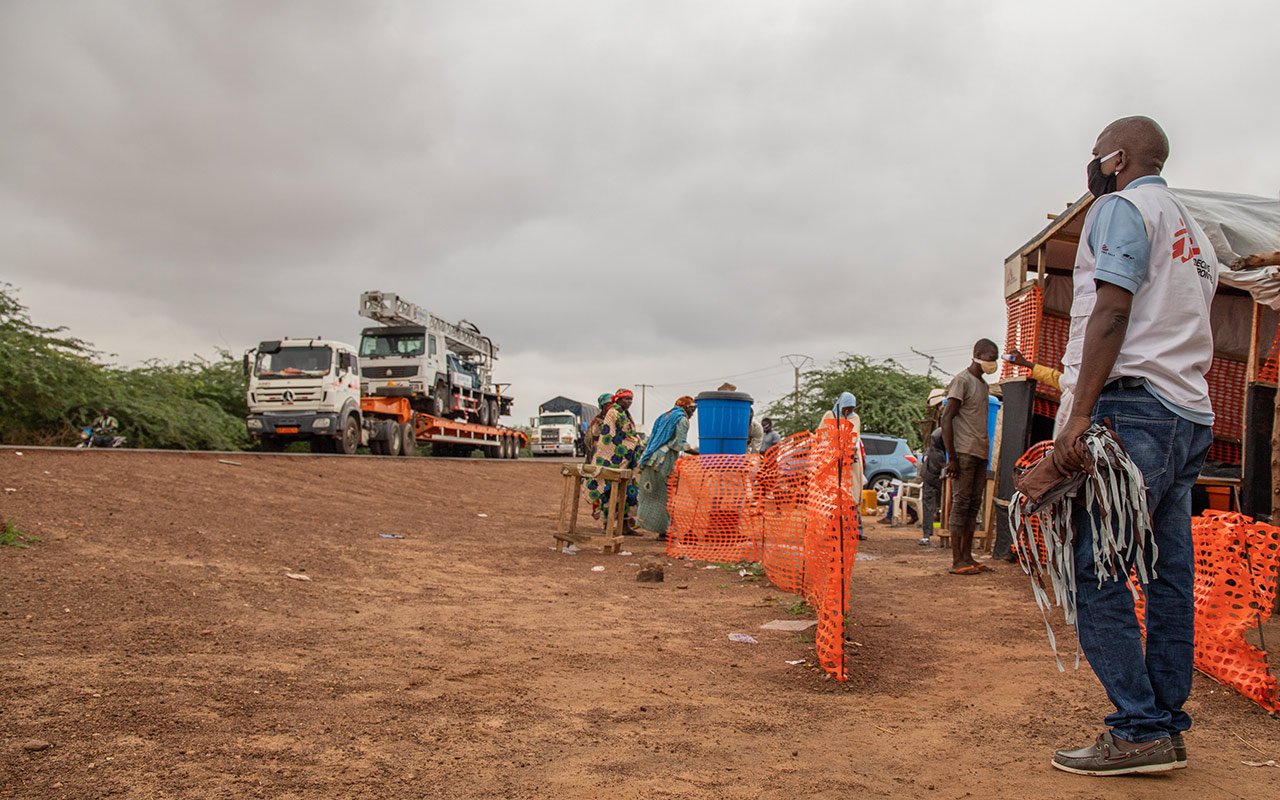 Distribution de masque à l’entrée de la ville de Zinder. À l’arrière-plan des camions attendent d’entrer dans la ville.