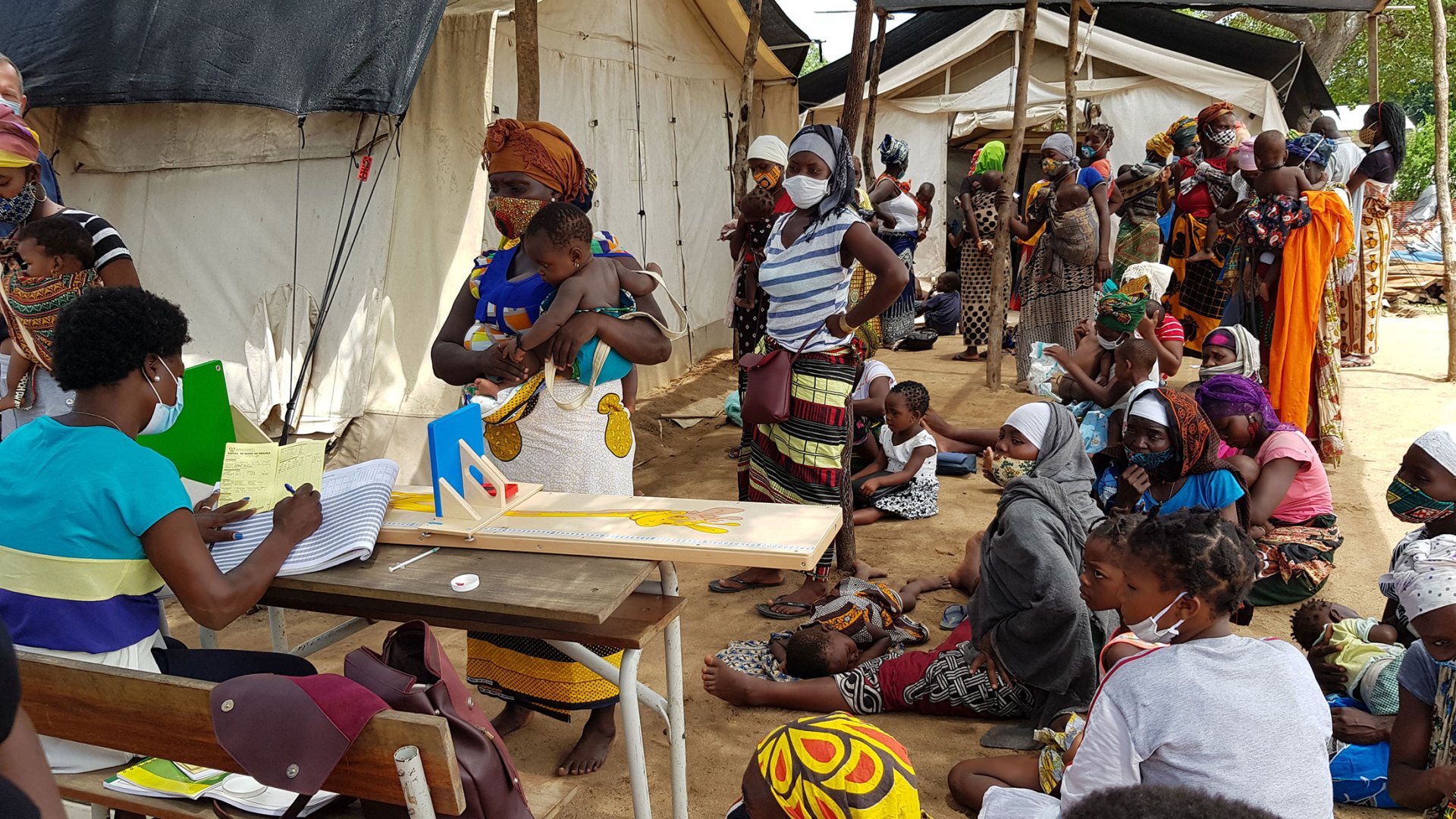 Des femmes font la file devant une infirmière MSF avec leur bébé dans les bras.