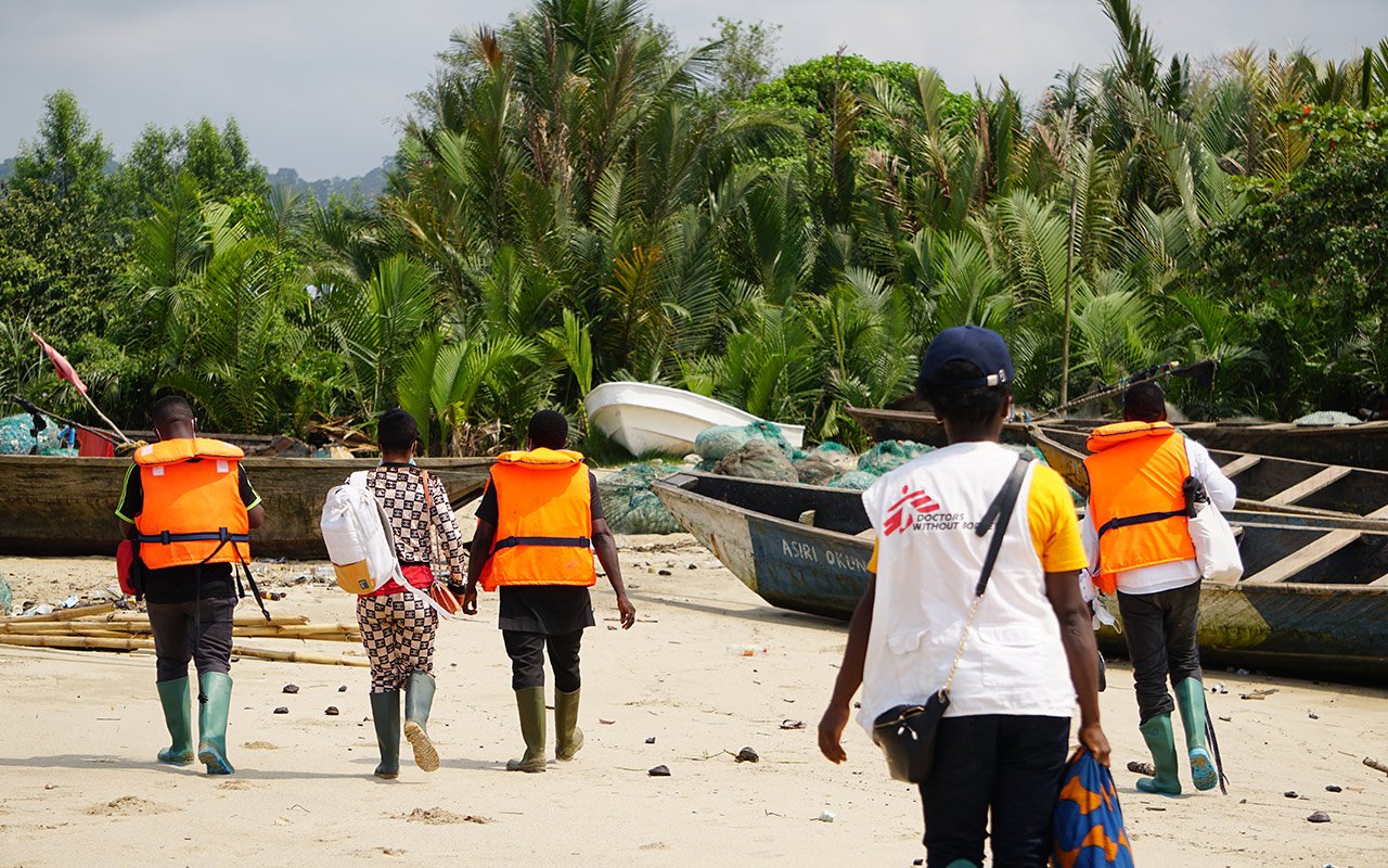 Une équipe MSF marche sur le sable pour atteindre le village d'Enyenge où ils mènent le deuxième jour de la campagne de vaccination contre le choléra. Enyenge, Sud-Ouest du Cameroun, 17 février 2022