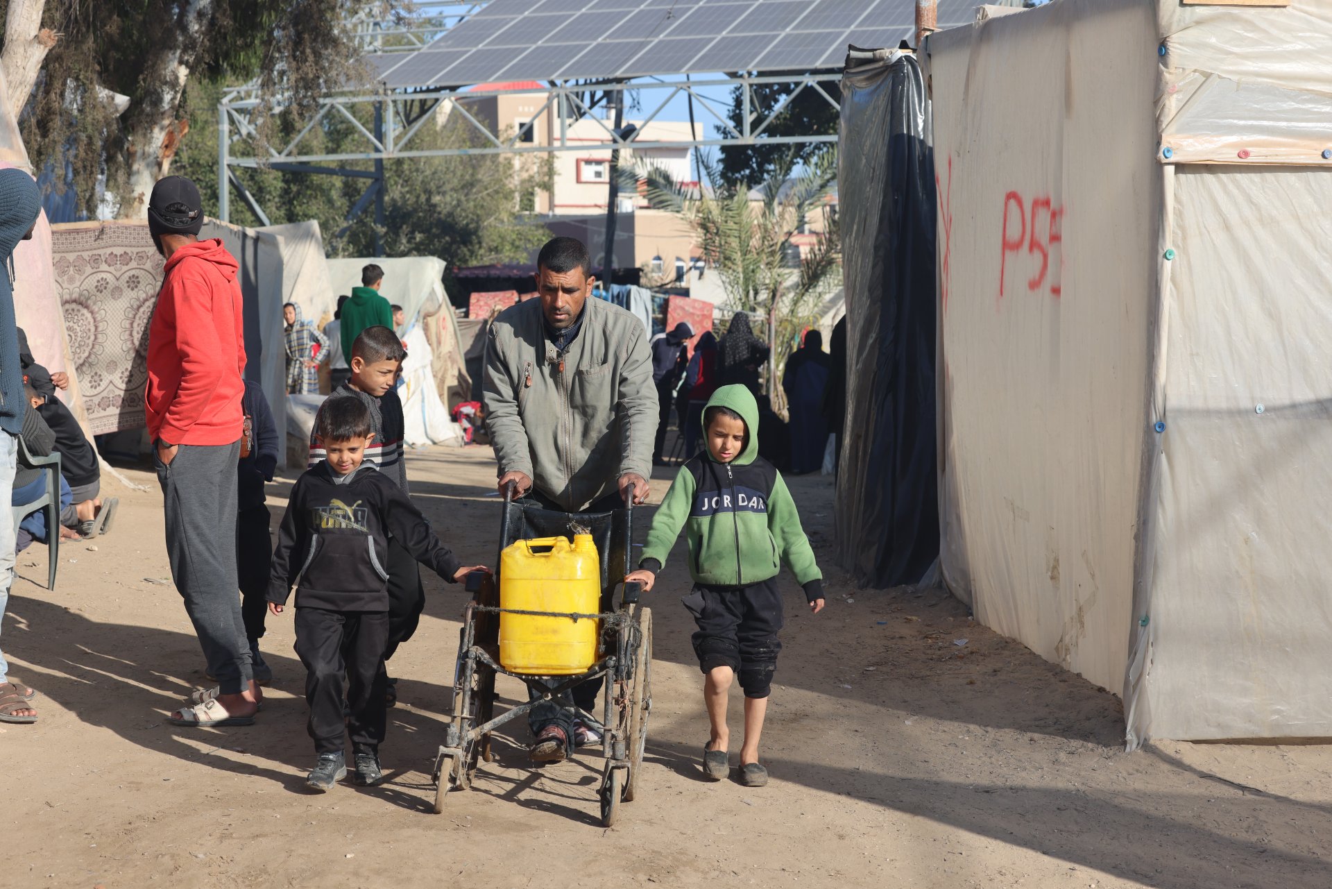 n père et ses deux enfants, tous trois déplacés à Rafah, rapportant de l’eau. Février 2024. ©MSF