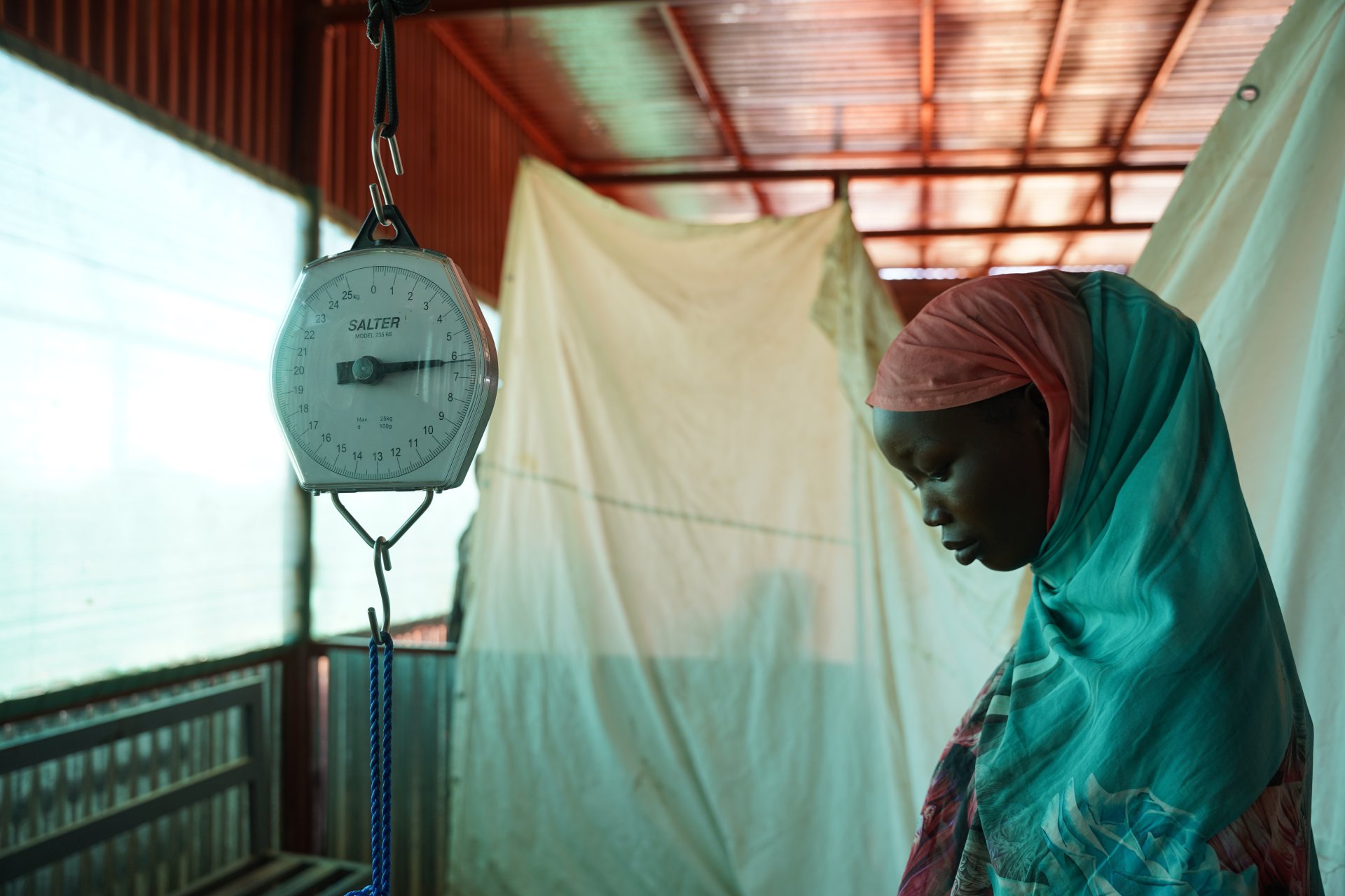 Frau wird gewogen bei einer Untersuchung im Ärzte Ohne Grenzen Spital im ZamZam Camp, 15 km südöstlich der Stadt El Fasher, Sudan. Hier leben mehr als 300 000 geflüchtete Menschen. Nord-Darfur, Februar 2024. 