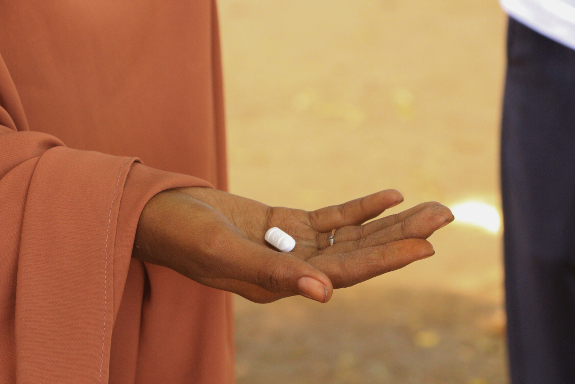 Une femme réfugiée tenant dans sa main le médicament Praziquantel, utilisé pour traiter la schistosomiase. 