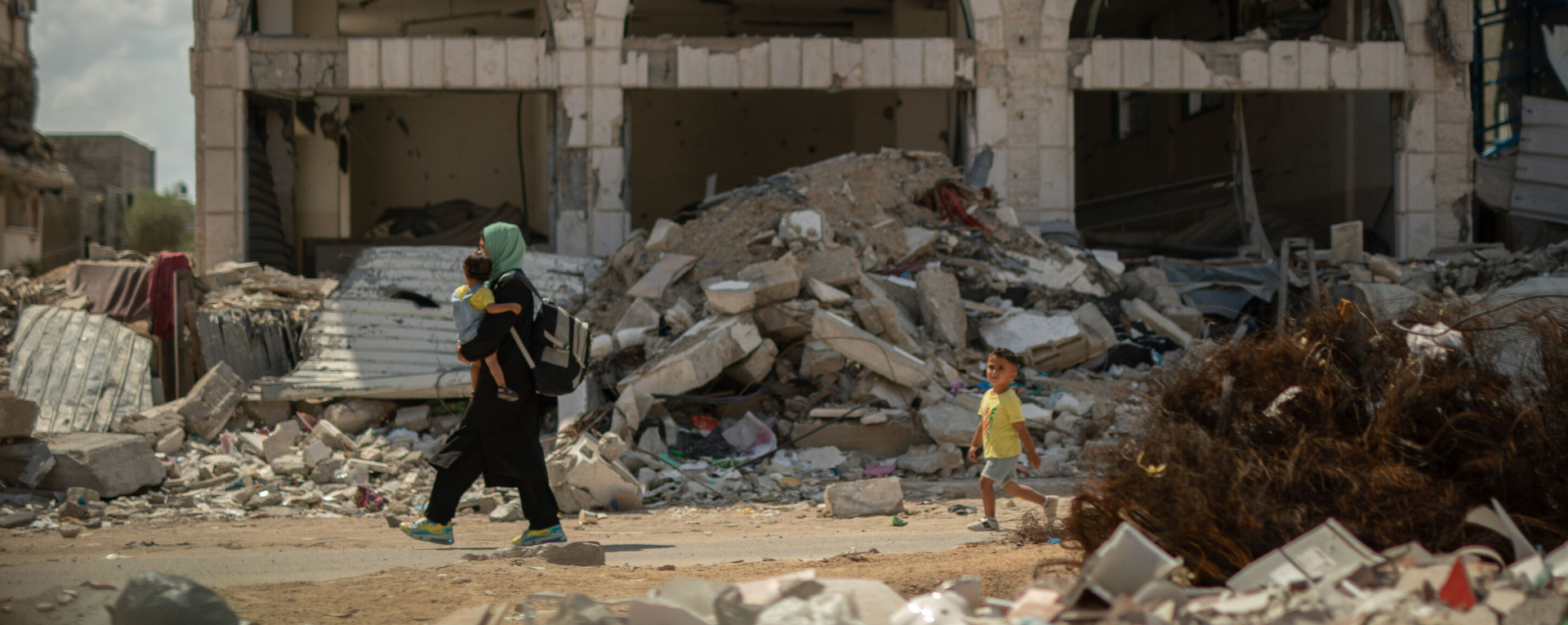 Dans le quartier de Shujaeyya à Gaza, une femme porte son enfant pour rentrer chez elle à travers les décombres.