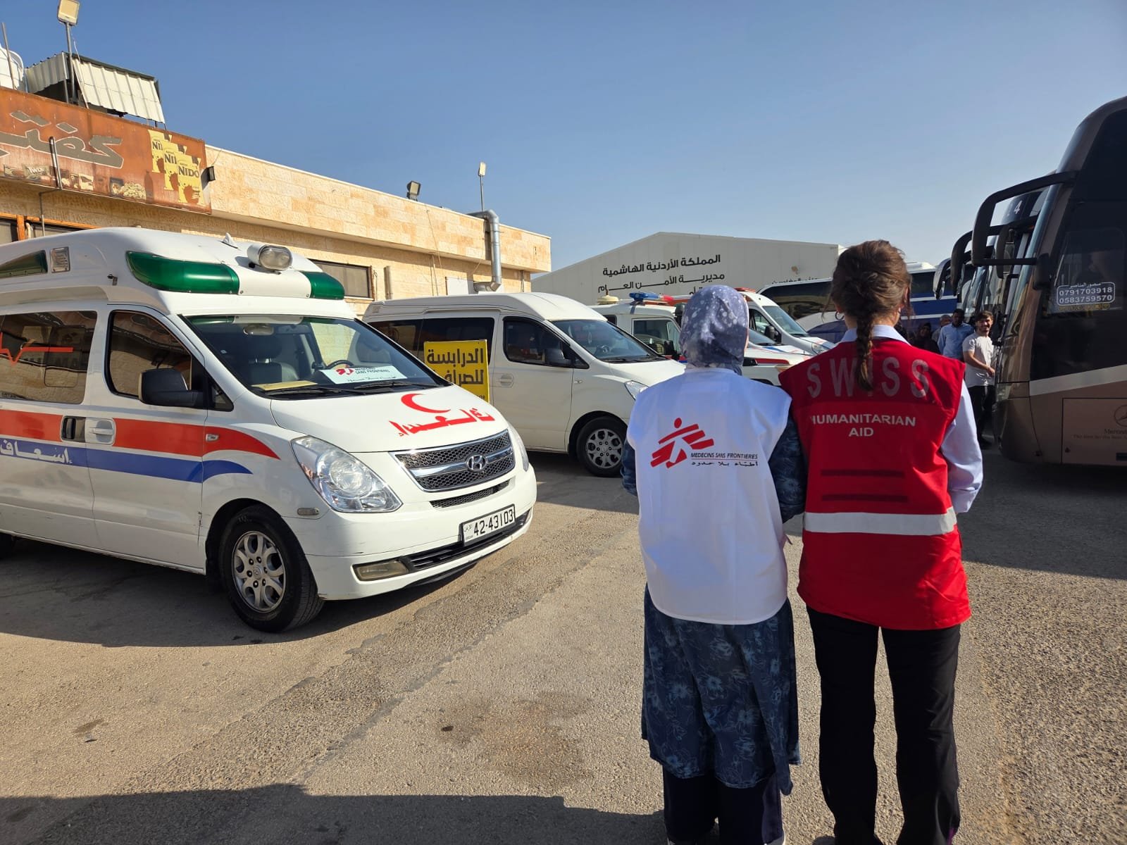 Deux personnes se tenant debout devant une ambulance Médecins Sans Frontières et Croissant-Rouge Jordanien.