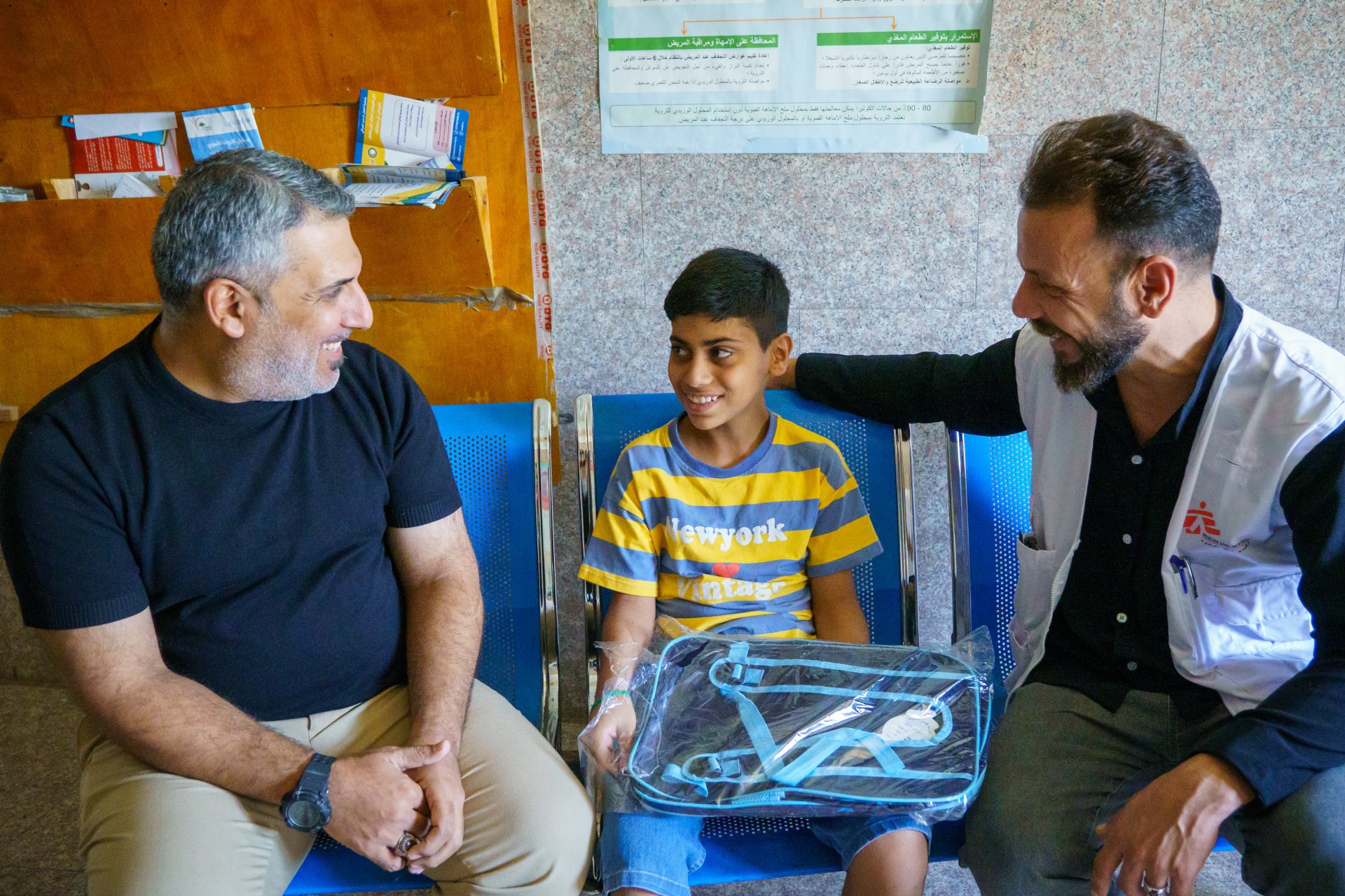 Abu Al-Fadl, un jeune garçon chez qui une tuberculose a été diagnostiquée très tôt, est assis avec son père et un agent de promotion de la santé de MSF au centre de santé Mustafa Al-Adhari, à Sadr City.