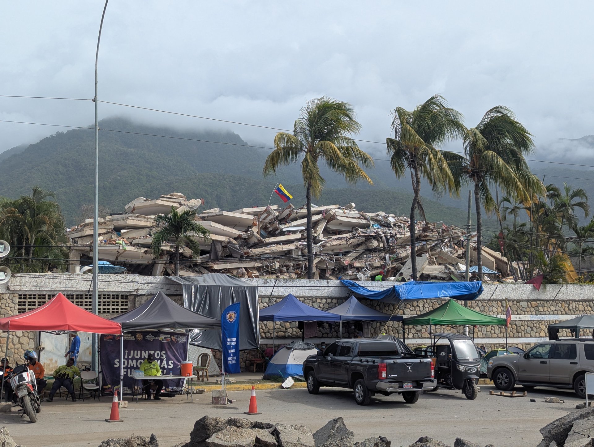 Le drapeau vénézuélien flotte au-dessus des décombres d'un immeuble effondré à La Guaira, ce mardi 21 juillet 2026. Cette région côtière est la plus touchée par les récents séismes dévastateurs.