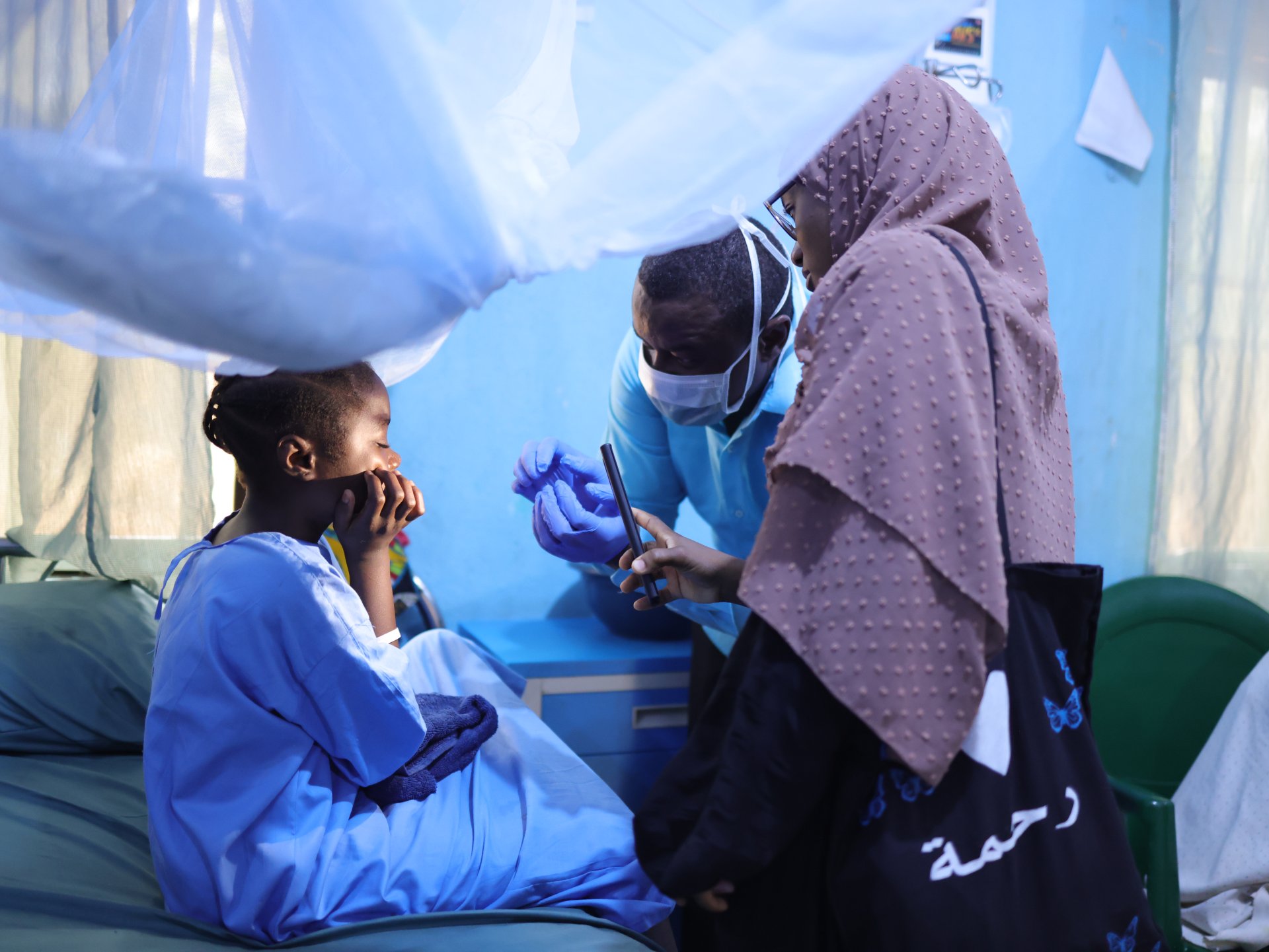 Un chirurgien du ministère de la Santé et un kinésithérapeute de Médecins Sans Frontières (MSF) examinent Maryam Bashir, âgée de 12 ans, trois jours après qu’elle a subi une intervention de chirurgie reconstructive du nez à l’hôpital pour enfants de Noma, soutenu par MSF, dans l’État de Sokoto, au Nigeria.