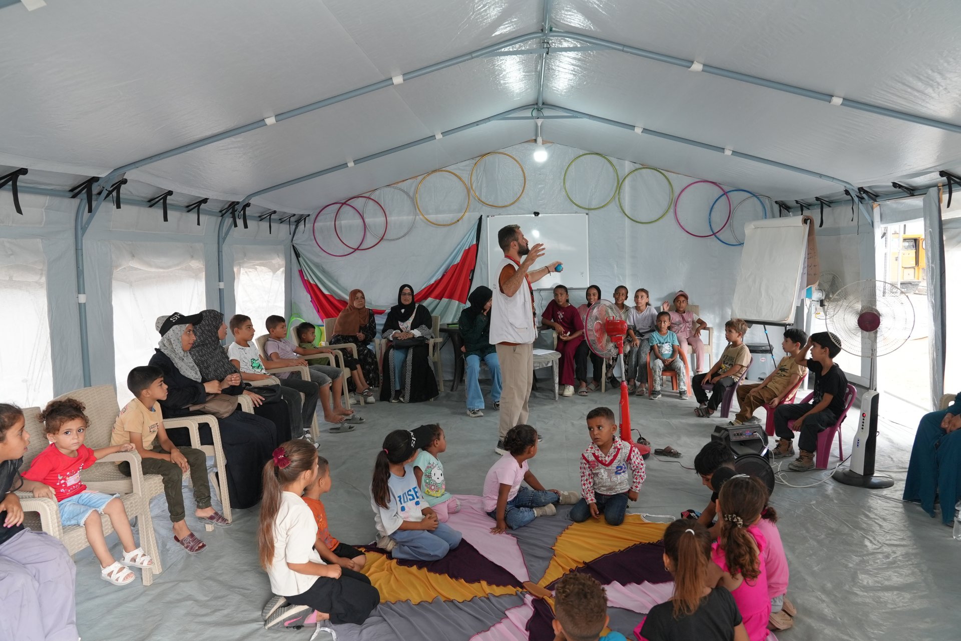 Mahmoud Al-Balbisi, conseiller en santé mentale chez Médecins Sans Frontières (MSF), anime une séance ludique et pédagogique destinée aux enfants et à leurs accompagnants à l'intérieur d'une des tentes du poste de soins.