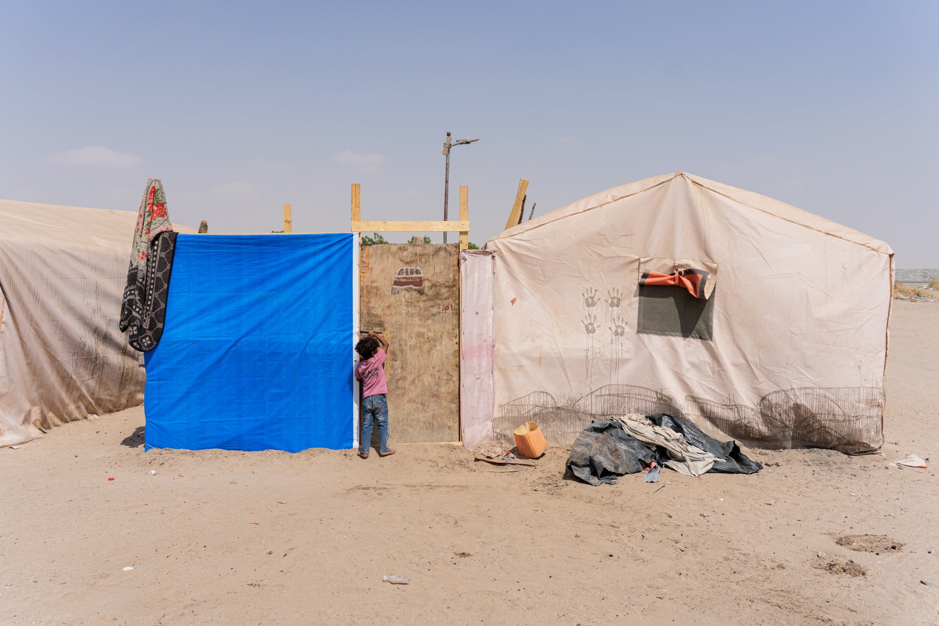 Une petite fille frappe à la porte de sa tente, à l'entrée du camp d'Atira, dans le gouvernorat de Lahj. 