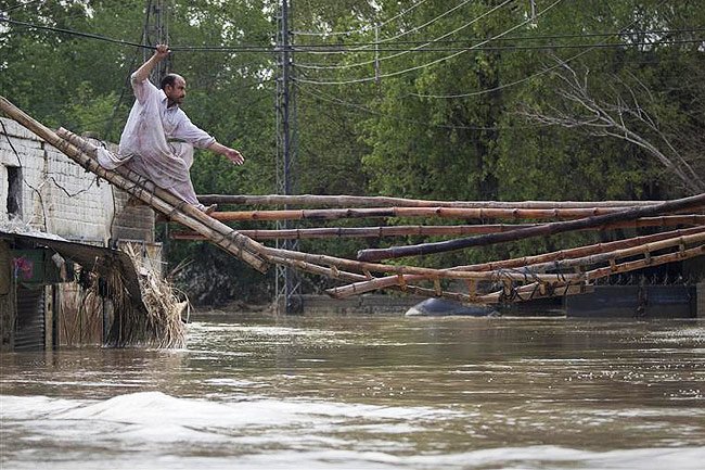 Un homme tente de quitter sa maison inondée en traversant un pont de fortune à Nowshera, au Pakistan dans la province du nord-ouest de Khyber Pakhtunkhwa. 31/07/2010