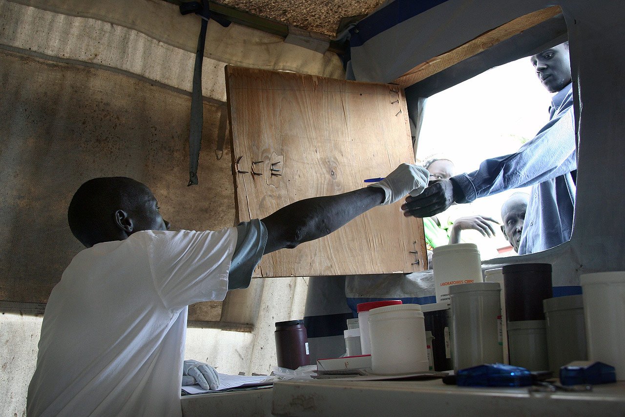 Dans le village de Pibor, les équipes de MSF effectuent plus de 5000 consultations mensuelles (2006), travaillant sous tente durant la construction d’un nouveau centre de soin de santé primaire. Pibor, Sud Soudan, 07/07/2006