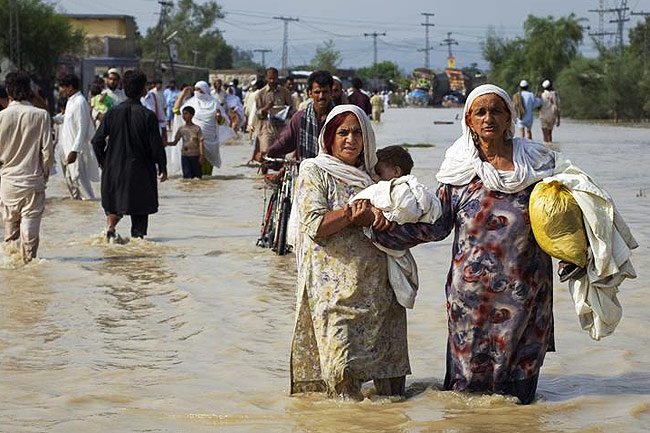 Des femmes avancent avec peine dans l’eau avec leurs enfants durant l’évacuation de Nowshera, dans la province du nord-ouest de Khyber Pakhtunkhwa au Pakistan. 31/07/2010.