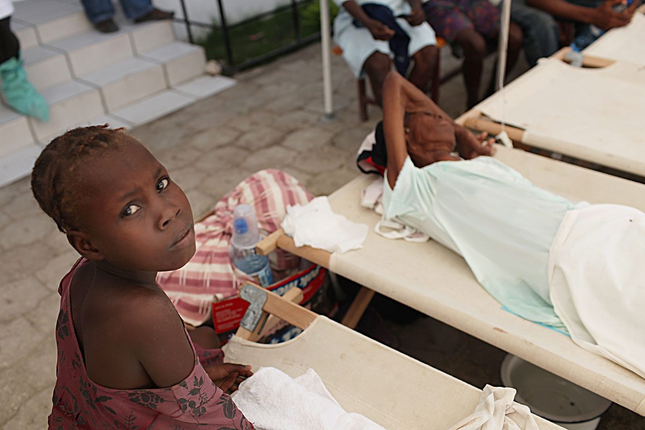 Une fille veille sur un membre de sa famille atteint des symptômes du choléra dans un hôpital de Saint-Marc dirigé par le gouvernement haïtien où MSF traite les patients de l’épidémie de choléra, Haïti, 27.10.2010