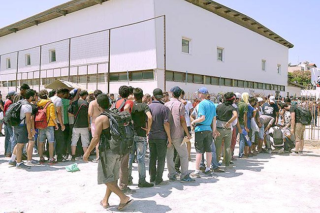 Les migrants font la file à l'extérieur du stade de Kos en attendant d'être enregistrés par la police grecque.
