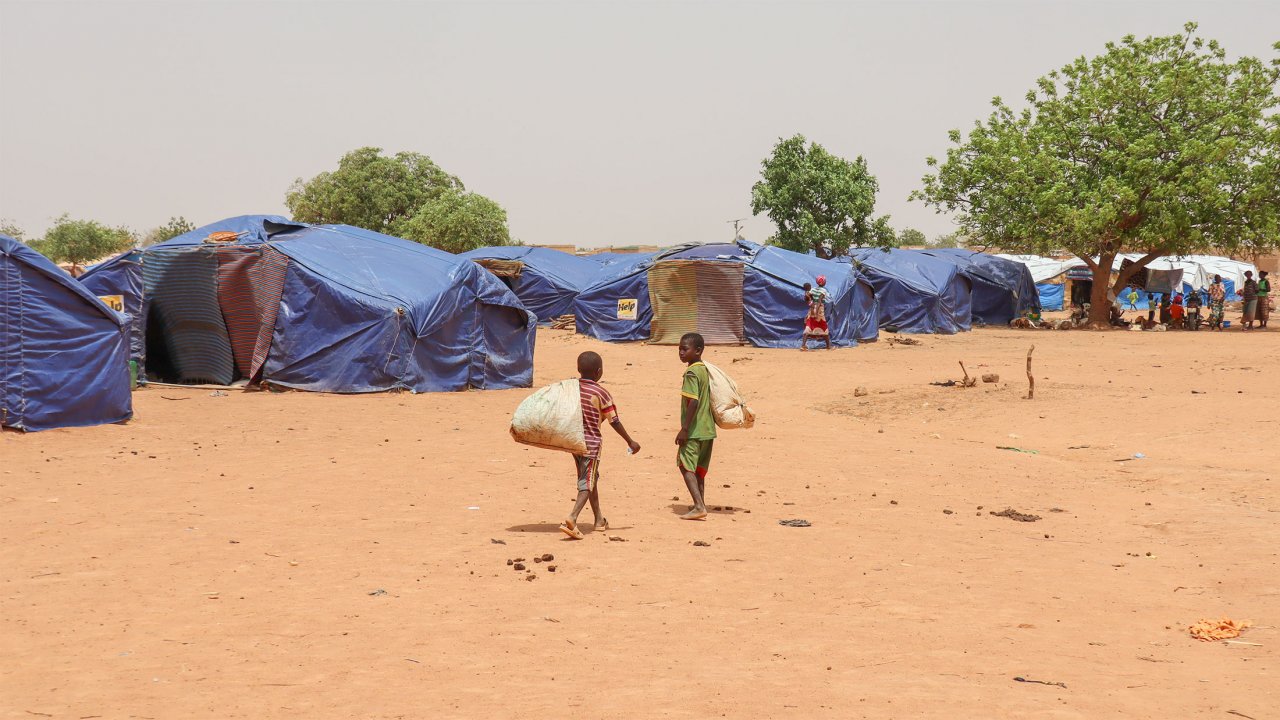 Le site de déplacés de Pissila. Deux enfants marchent devant les tentes du camp.