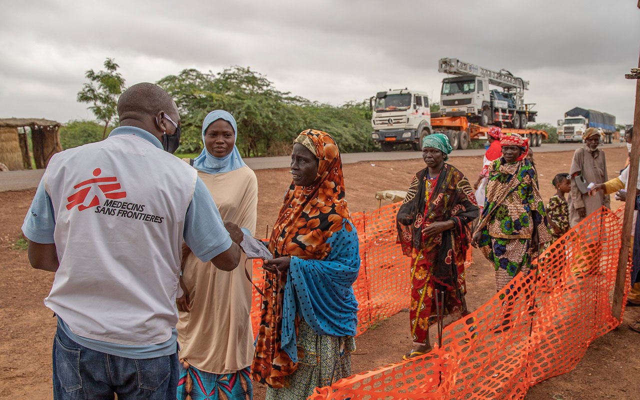 Distribution de masque et contrôle de la température à l’entrée de la ville de Zinder. À l’arrière-plan des camions attendent d’entrer dans la ville.
