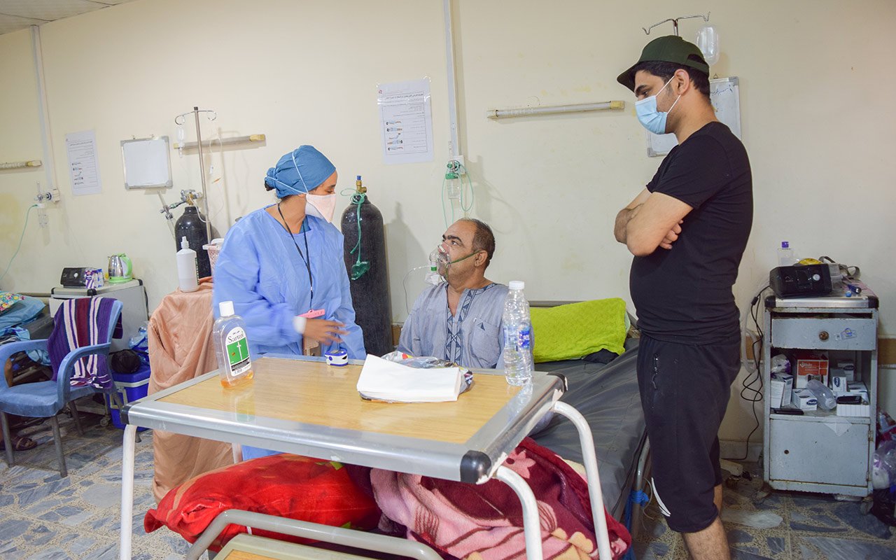 Ein Patient spricht im Beisein eines Angehörigen mit einer Pflegefachfrau auf der Beatmungsstation am Al-Kindy-Spital.