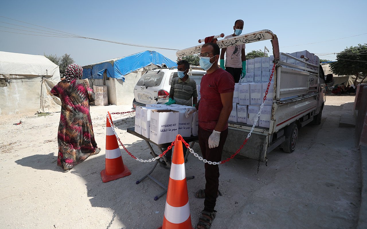 Deux hommes debout devant un camion se préparent à distribuer des kits d’hygiène. 