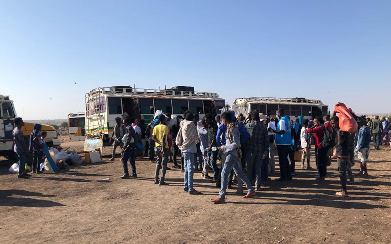 Un groupe attend devant les autocars qui vont les emmener de Hamdayet au camp de Um Rakuba.