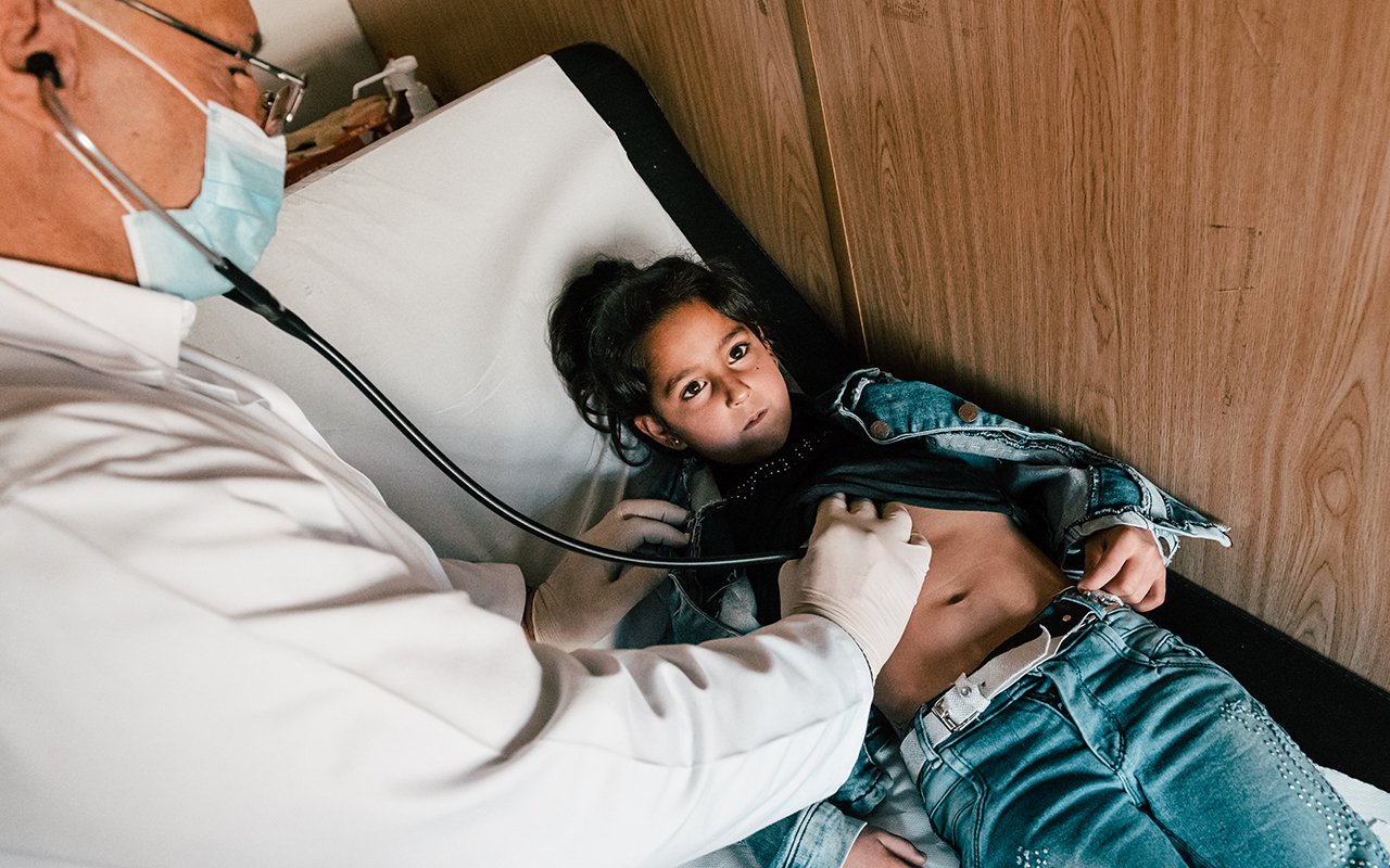 Ein Arzt mit einem Stethoskop untersucht ein kleines Mädchen.