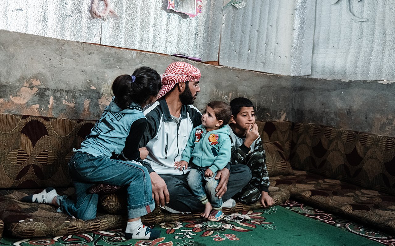 Un homme avec trois de ses enfants dans leur abri de fortune.