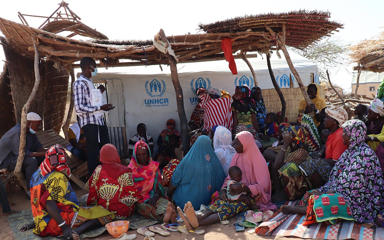 Des femmes assises par terre qui écoutent un promoteur de la santé MSF