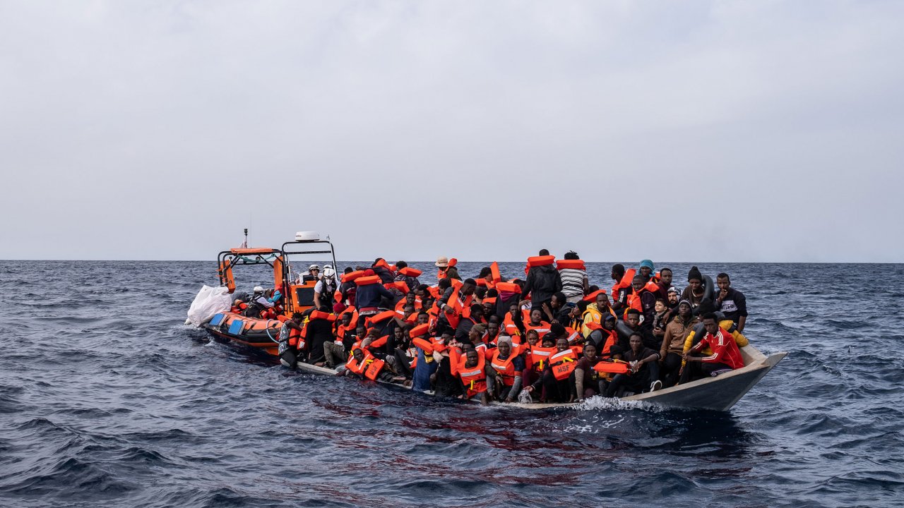 Als die Geo Barents das schiffbrüchige Holzboot erreicht, warten Moustafa und sein Sohn Ali geduldig am Bug des Bootes bis sie mit einer Rettungsweste versorgt werden.