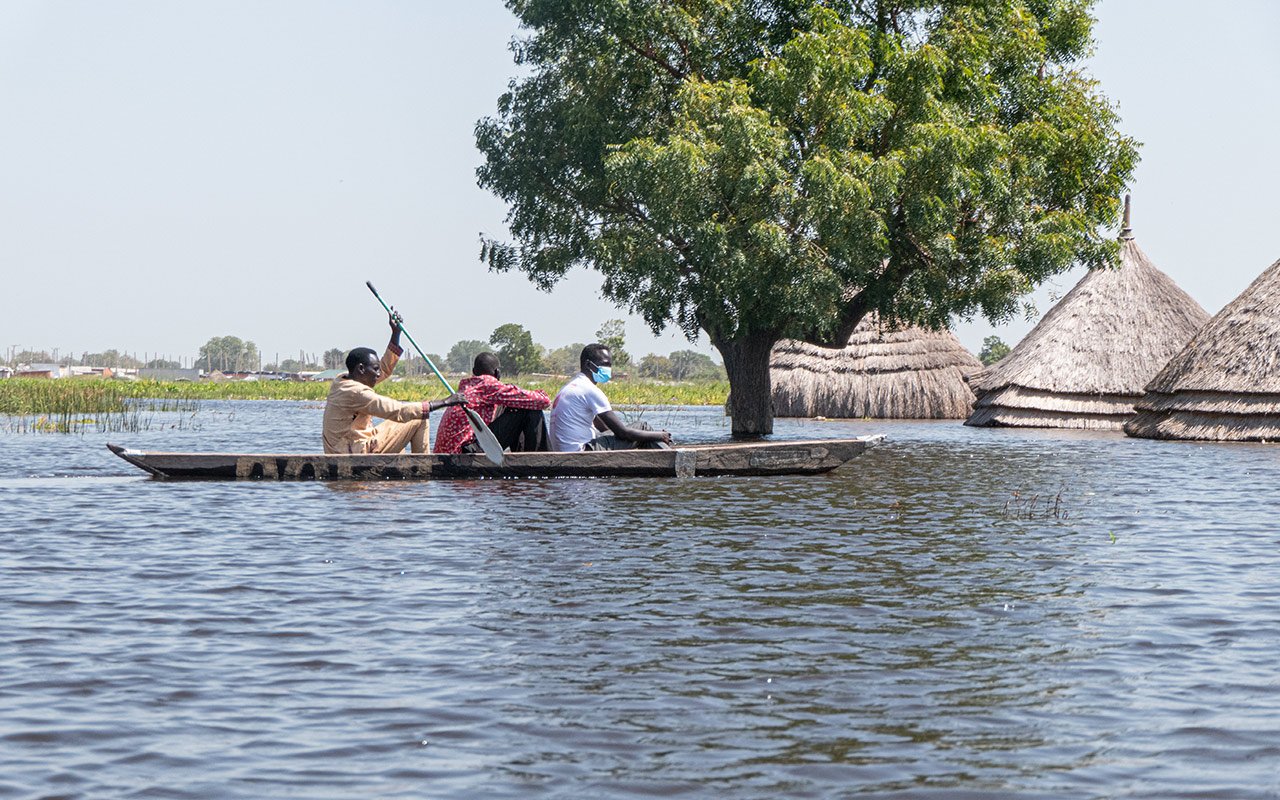 Des hommes en canoë naviguent sur les eaux de crue à Bentiu, dans l'État d'Unity, où les maisons et les moyens de subsistance (cultures et bétail) des habitants, ainsi que les centres de santé, les écoles et les marchés, sont complètement submergés par les eaux.