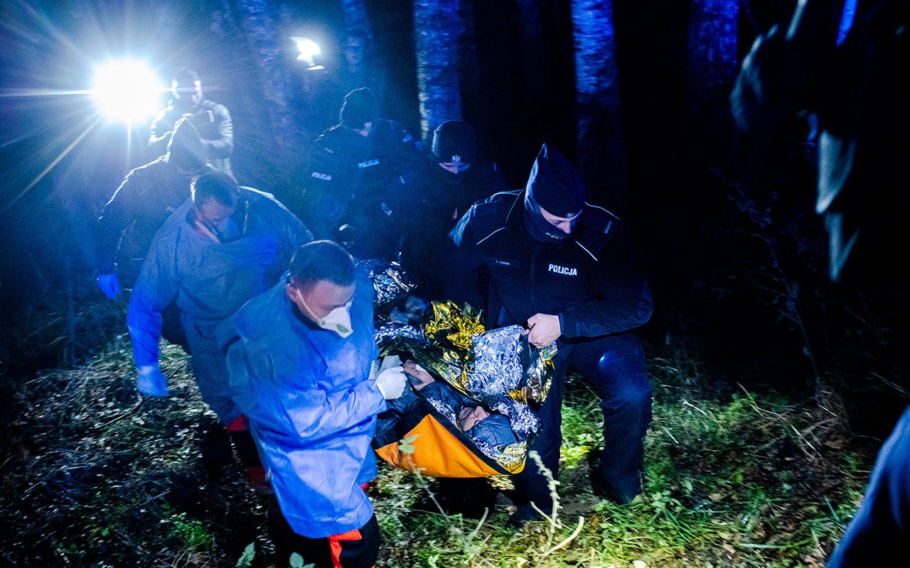 Un homme transporté en civière par des secouristes, de nuit.