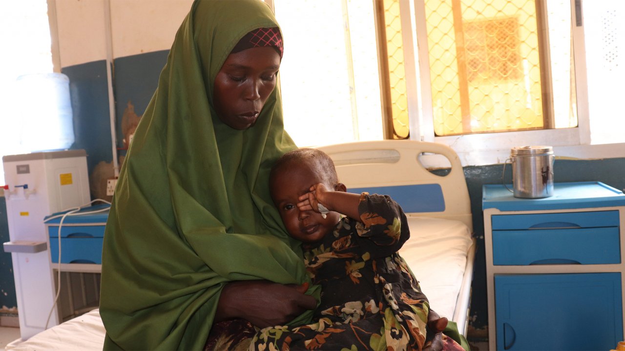 Dans l'unité d'isolement de l'hôpital de Bay, Abay (mère) tient dans ses bras sa fille malade de la rougeole depuis une semaine.