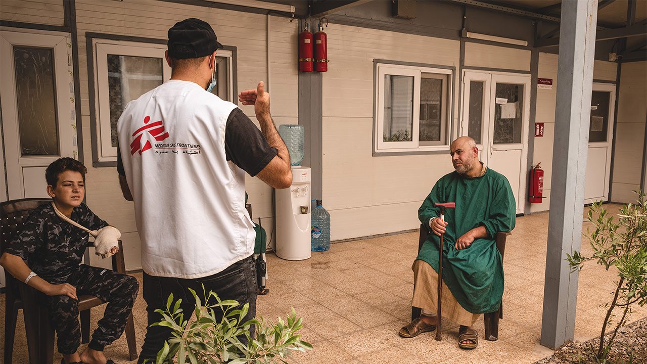 Faris, sur une chaise, écoute le promoteur de santé.