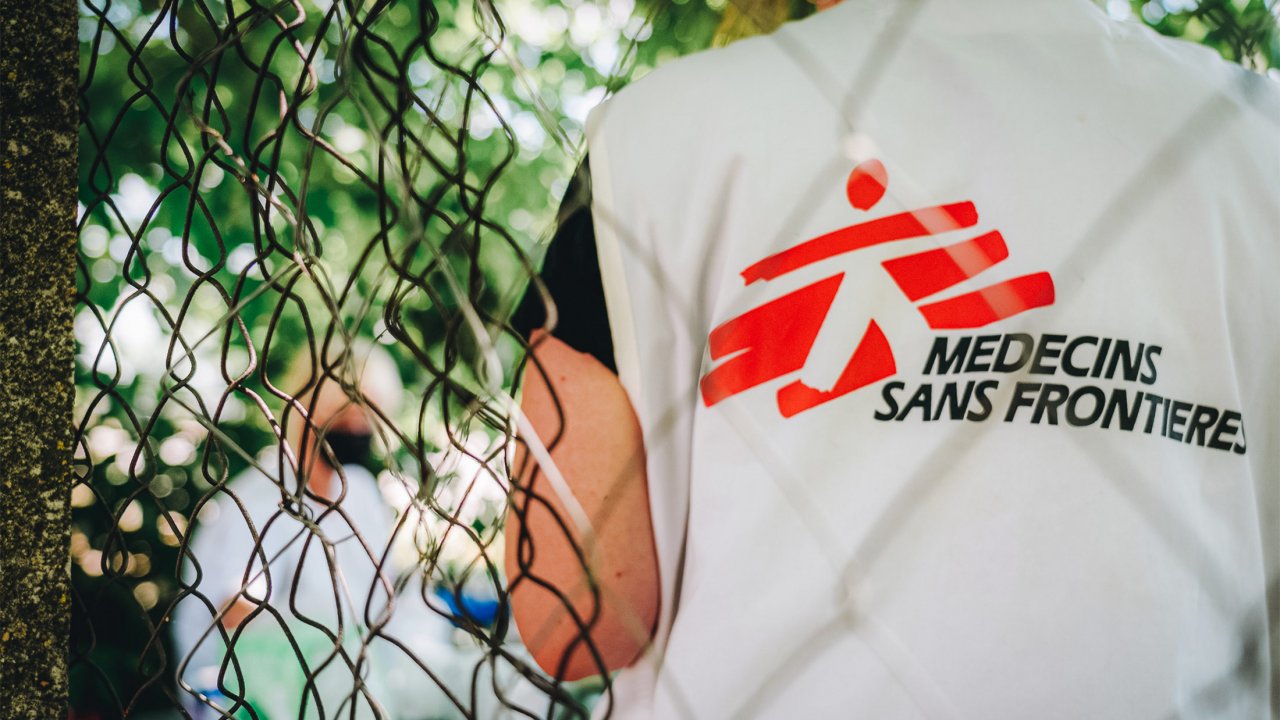 Ein MSF-Mitarbeiter steht neben einem Stacheldrahtzaun während einer medizinischen Konsultation in einer mobilen Klinik im Grenzgebiet in Serbien.
