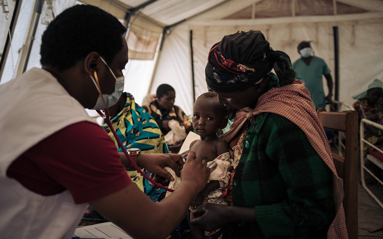 Le docteur MSF Benjamin Safari examine Emeriane, 11 mois, dans le service pédiatrique sous les tentes du centre de santé géré par MSF du camp de Rhoe. République démocratique du Congo. 23 décembre 2021