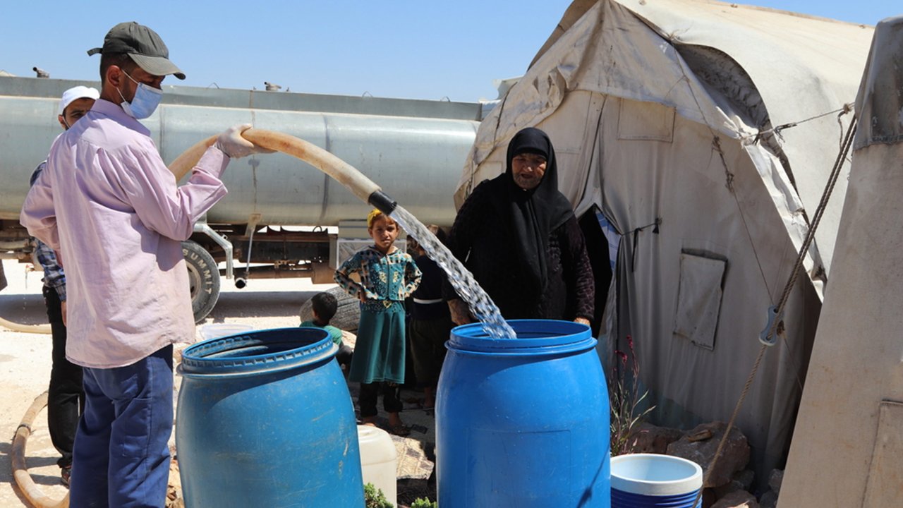 Les équipes MSF remplissent d'eau potable le réservoir d'une vieille femme déplacée dans un camp du nord-ouest de la Syrie.
