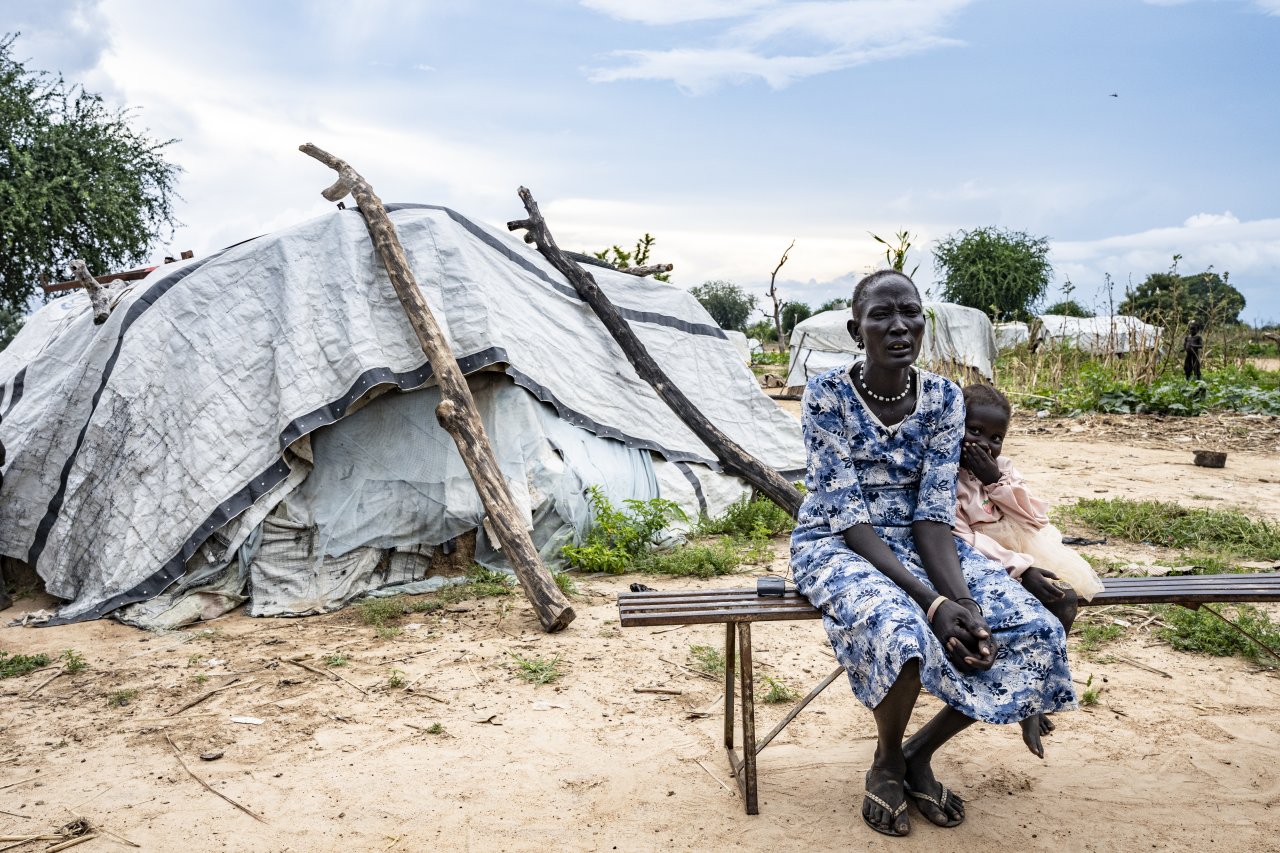 Der 32-jährige Arual Manyok und seine dreijährige Tochter Adit Ayuel, die eine Malariabehandlung (MDA) erhalten haben, unterhalten sich mit unseren Mitarbeitenden vor ihrem Tukul.
