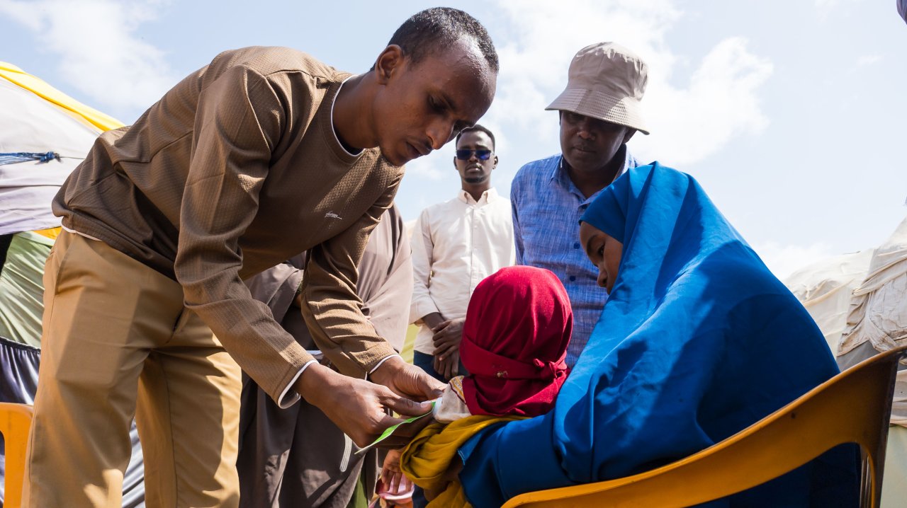 Mohamud Moktar, agent de santé communautaire, mesure le périmètre du bras à mi-hauteur (MUAC) d’un enfant dans un camp de personnes déplacées à Baidoa, en Somalie.