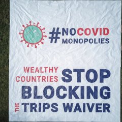 Aus der Ferne sieht man ein grosses Transparent mir der Aufschrift: «#No Covid Monopolies, wealthy countries stop blocking the TRIPS Waiver»
