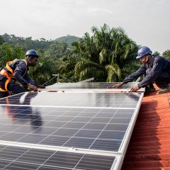 2 hommes posent un panneau solaire sur le toit de l’hôpital