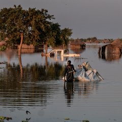 Un homme marche dans un village inondé. 