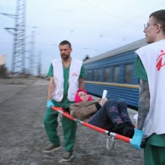 Deux staffs MSF portent une patiente sur un brancard.